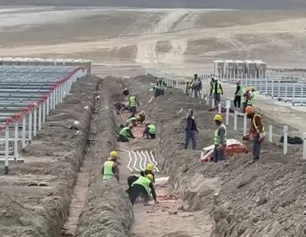 Workers installing cable trenches and solar panels at Garadagh Solar Power Plant